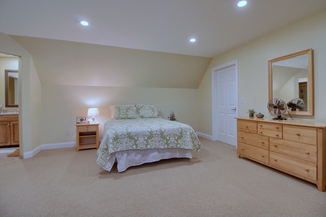 bedroom with ensuite bath, light carpet, and lofted ceiling