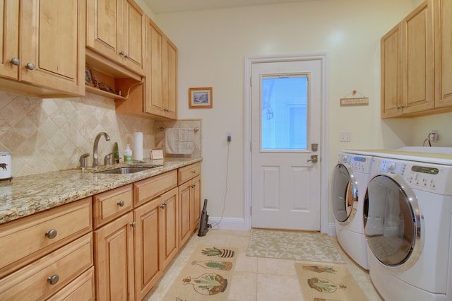 laundry room with washing machine and clothes dryer, sink, light tile patterned flooring, and cabinets