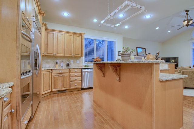 kitchen with stainless steel dishwasher, a kitchen breakfast bar, light hardwood / wood-style floors, and a kitchen island