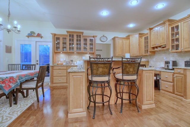 kitchen featuring a center island, light stone countertops, hanging light fixtures, and light hardwood / wood-style flooring