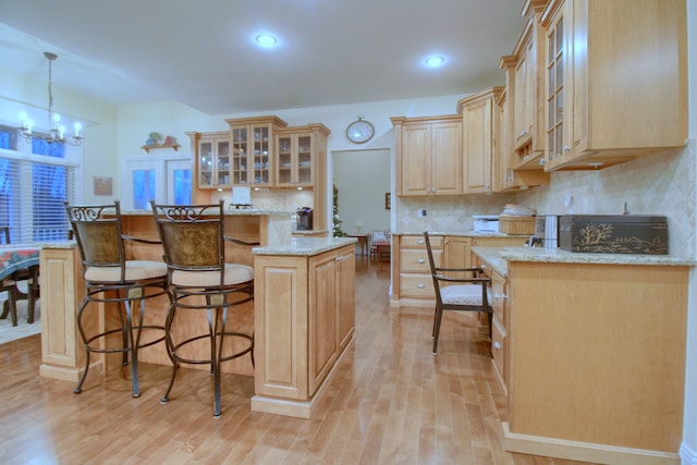 kitchen featuring a center island, hanging light fixtures, light brown cabinetry, light hardwood / wood-style floors, and a chandelier