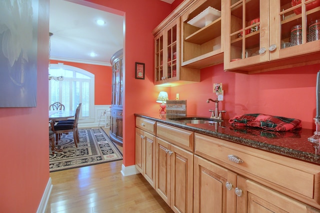 kitchen with dark stone counters, an inviting chandelier, sink, light hardwood / wood-style flooring, and ornamental molding