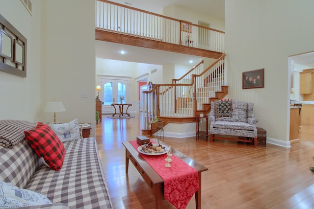 living room with light wood-type flooring, french doors, and a towering ceiling