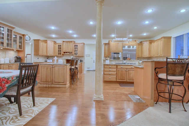 kitchen featuring light hardwood / wood-style floors, ornate columns, and appliances with stainless steel finishes