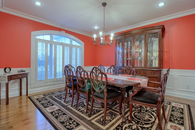 dining area with a chandelier, wood-type flooring, and ornamental molding