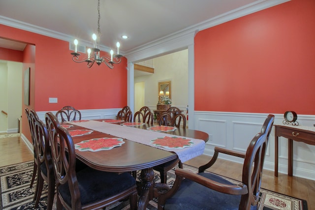 dining room with wood-type flooring, ornamental molding, and a chandelier