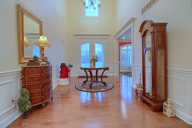 foyer entrance featuring a wealth of natural light, french doors, a notable chandelier, and light hardwood / wood-style flooring