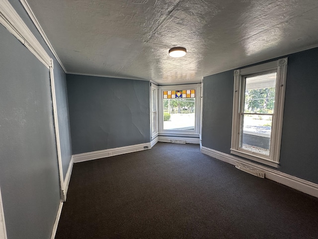 unfurnished room with ornamental molding, a healthy amount of sunlight, a textured ceiling, and dark colored carpet