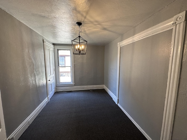 unfurnished dining area featuring dark colored carpet, a textured ceiling, and an inviting chandelier