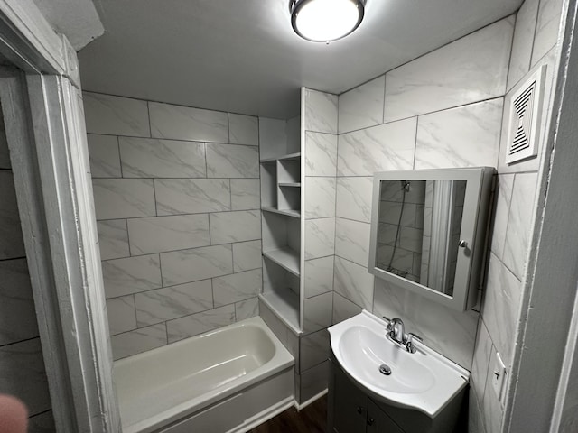 bathroom with vanity, tile walls, and tiled shower / bath combo