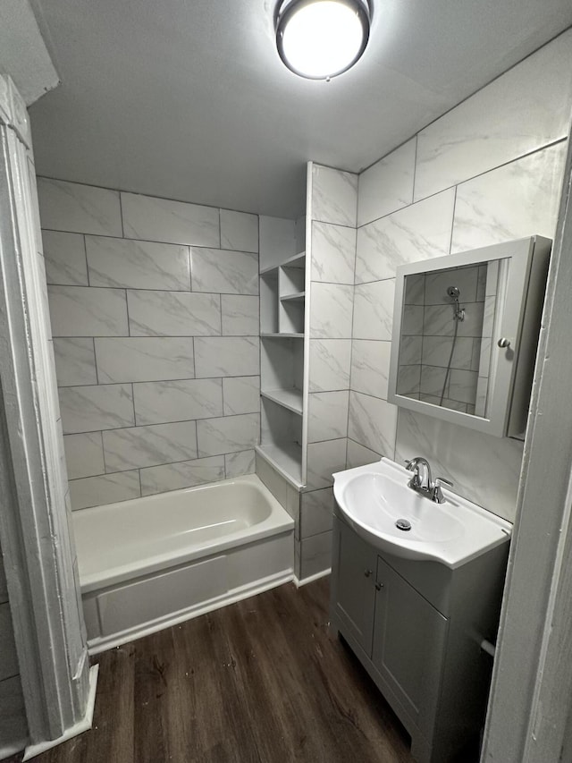 bathroom with bathtub / shower combination, vanity, hardwood / wood-style flooring, and tile walls