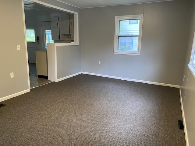 spare room featuring a wealth of natural light and dark carpet