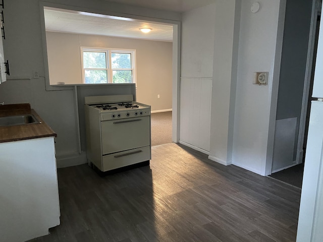 kitchen featuring dark hardwood / wood-style flooring, white cabinetry, sink, and gas range gas stove