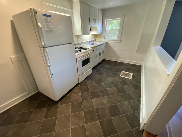 kitchen with white cabinetry, sink, dark tile patterned floors, and white appliances