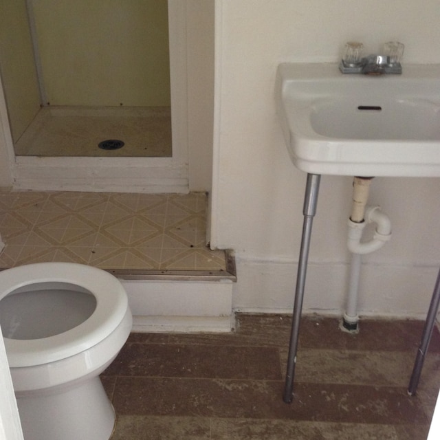 bathroom featuring sink, a shower, toilet, and backsplash