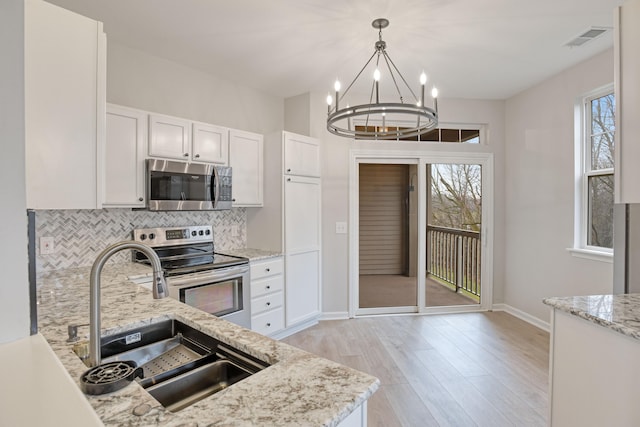 kitchen with light stone counters, stainless steel appliances, sink, light hardwood / wood-style floors, and white cabinetry