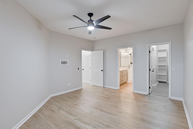 unfurnished bedroom featuring ensuite bathroom, ceiling fan, light hardwood / wood-style flooring, a spacious closet, and a closet