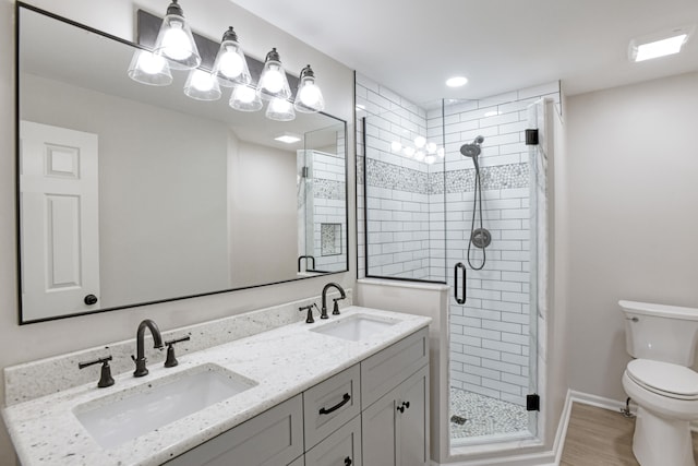 bathroom featuring toilet, wood-type flooring, a shower with door, and vanity