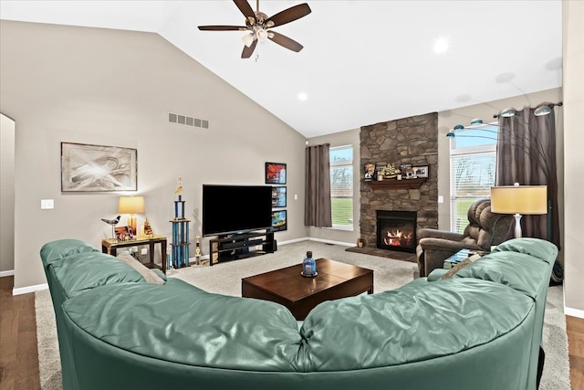 living room with ceiling fan, wood-type flooring, a fireplace, and high vaulted ceiling