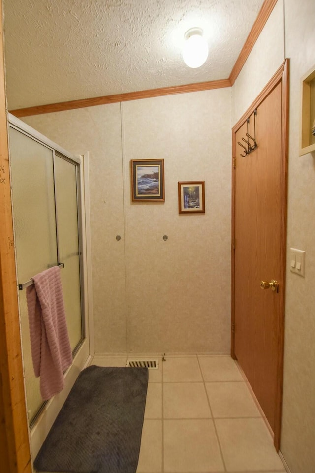 bathroom featuring tile patterned floors, ornamental molding, walk in shower, and a textured ceiling