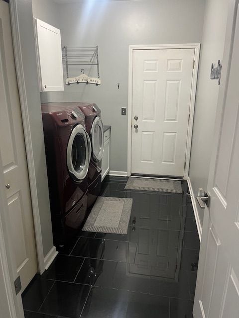 clothes washing area featuring washer and clothes dryer, cabinets, and dark tile patterned flooring