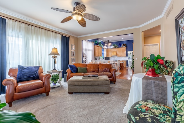 living room featuring ceiling fan with notable chandelier, ornamental molding, and a wealth of natural light