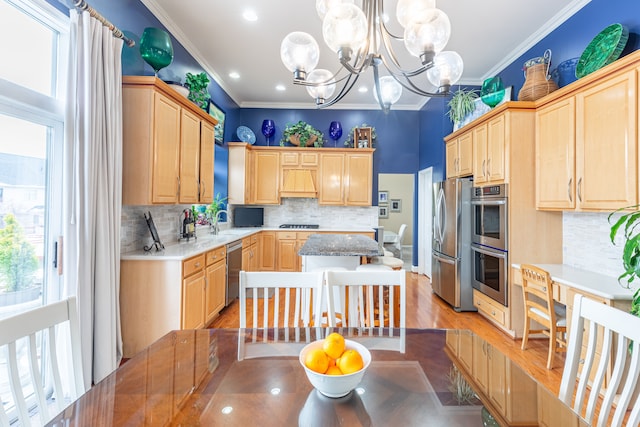 kitchen with light brown cabinets, stainless steel appliances, a notable chandelier, crown molding, and light wood-type flooring