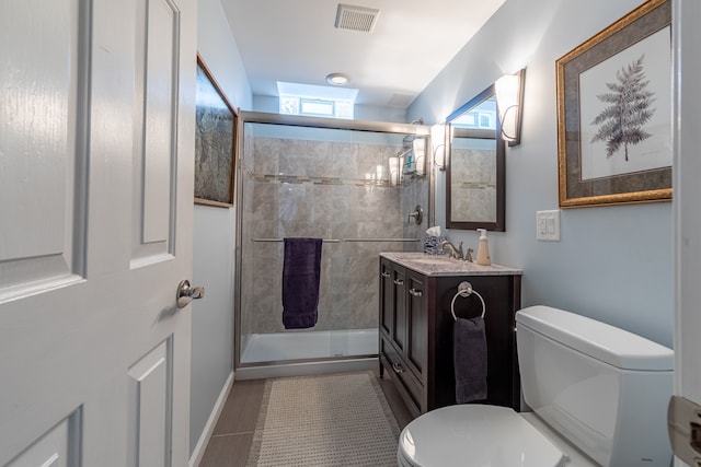 bathroom featuring tile patterned flooring, vanity, toilet, and a shower with door