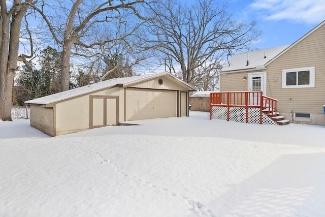 snowy yard featuring a garage and an outdoor structure