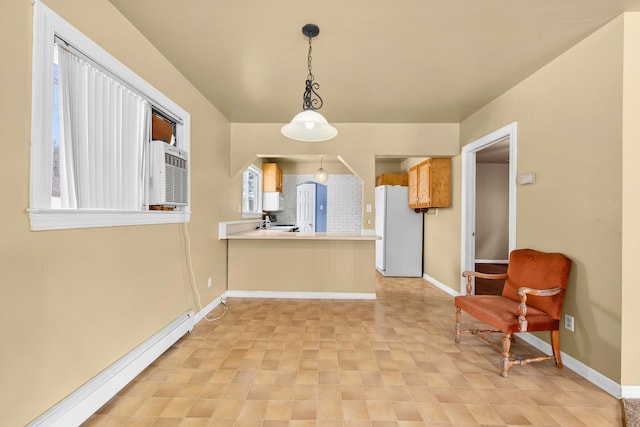 interior space featuring decorative light fixtures, white appliances, kitchen peninsula, and a baseboard radiator