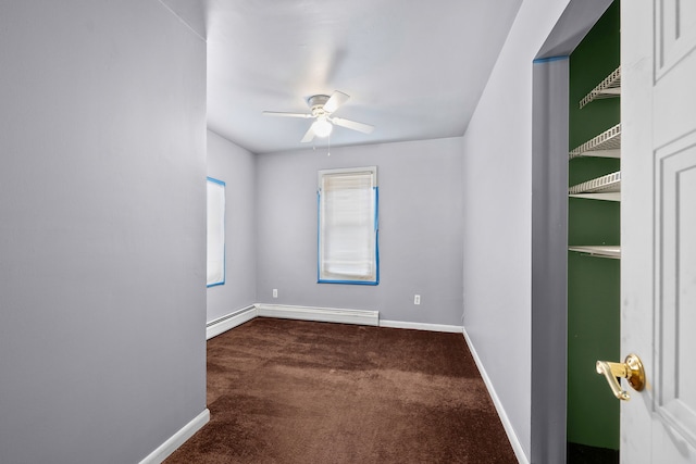 empty room featuring ceiling fan, dark carpet, and a baseboard heating unit