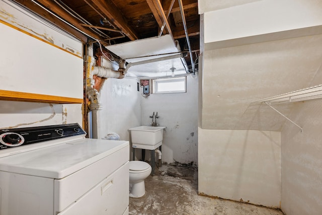 bathroom featuring toilet, washer / dryer, concrete flooring, and sink