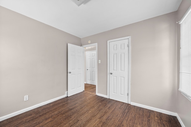 unfurnished bedroom with multiple windows and dark wood-type flooring