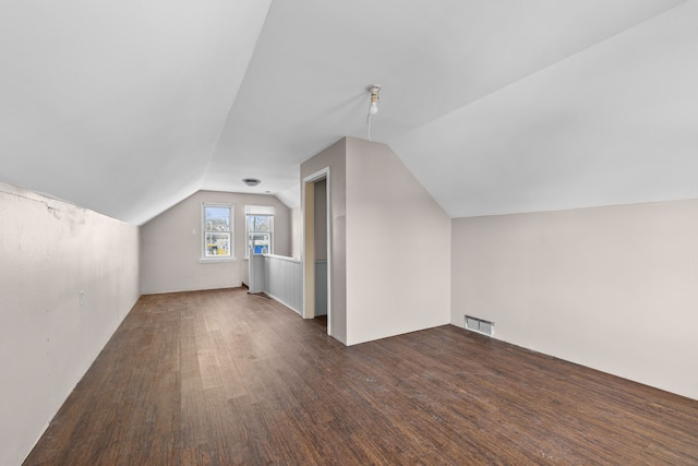 additional living space featuring dark wood-type flooring and vaulted ceiling