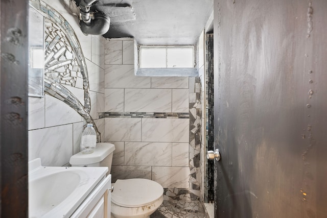 bathroom featuring vanity, toilet, and tile walls