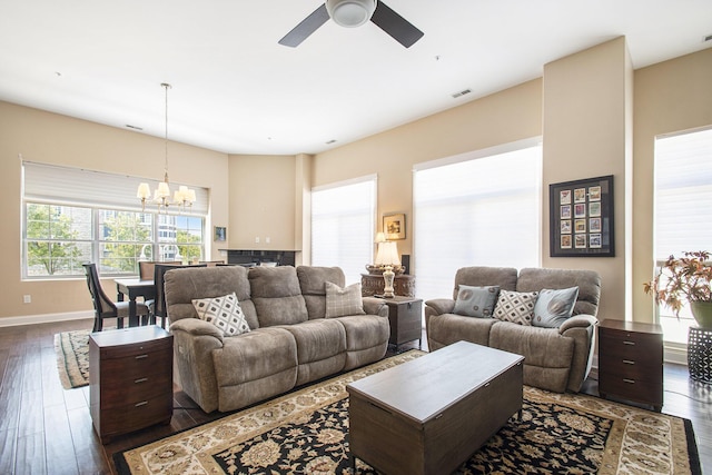 living room featuring ceiling fan with notable chandelier and dark wood-type flooring