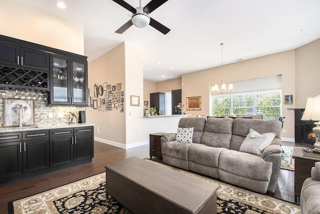 living room with ceiling fan with notable chandelier and dark wood-type flooring