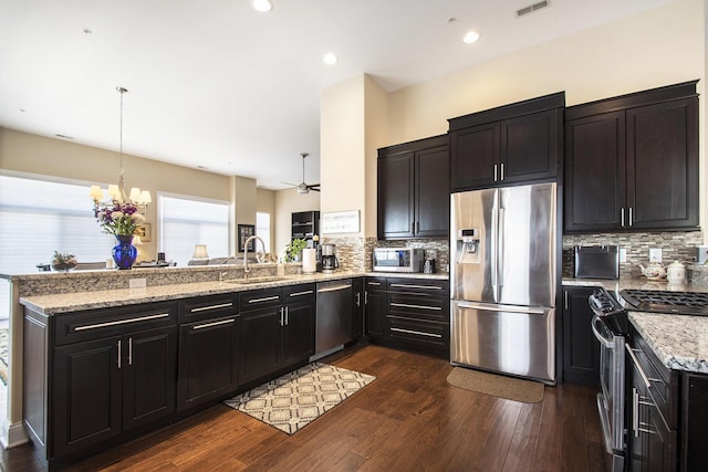 kitchen featuring dark wood-type flooring, sink, decorative light fixtures, kitchen peninsula, and stainless steel appliances