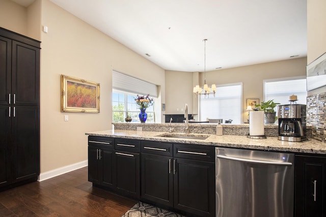 kitchen with sink, hanging light fixtures, stainless steel dishwasher, light stone countertops, and dark hardwood / wood-style flooring