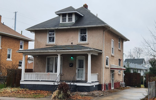 traditional style home with covered porch, fence, and stucco siding