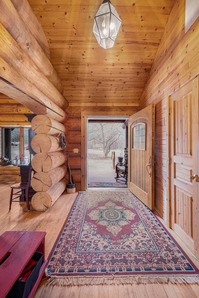 foyer entrance with log walls, hardwood / wood-style floors, high vaulted ceiling, and wood ceiling