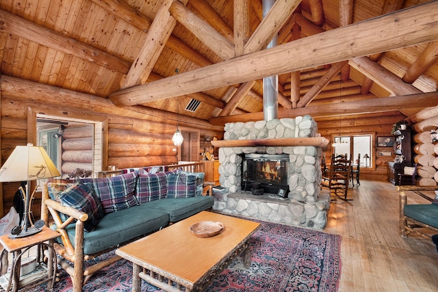 living room with beam ceiling, log walls, a stone fireplace, light hardwood / wood-style flooring, and high vaulted ceiling