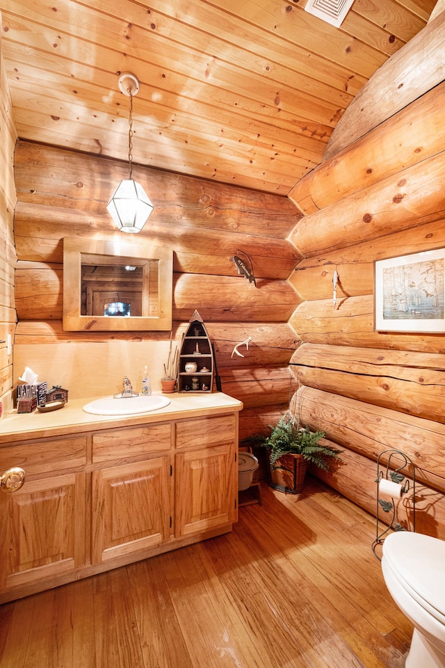 bathroom featuring vanity, hardwood / wood-style flooring, toilet, rustic walls, and wood ceiling