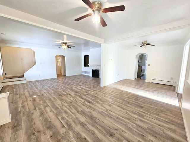 unfurnished living room featuring ceiling fan, wood-type flooring, and a baseboard heating unit