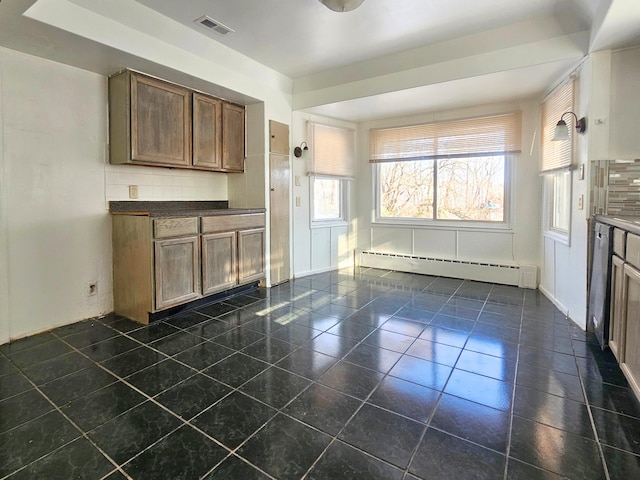 kitchen featuring backsplash, baseboard heating, and dark tile patterned flooring