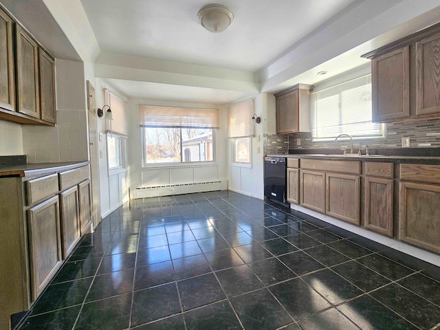 kitchen featuring decorative backsplash, black dishwasher, a healthy amount of sunlight, and a baseboard heating unit