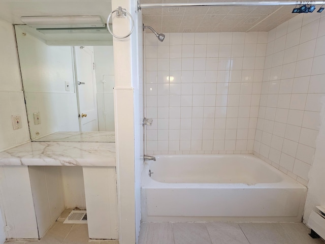 bathroom featuring tile patterned flooring, tiled shower / bath combo, and a baseboard heating unit