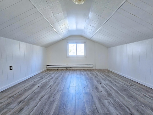 additional living space with hardwood / wood-style floors, baseboard heating, and lofted ceiling