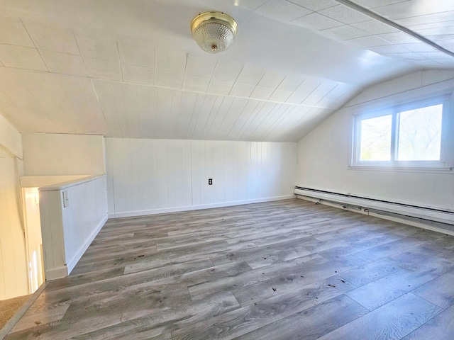 bonus room with wood-type flooring, vaulted ceiling, and a baseboard heating unit