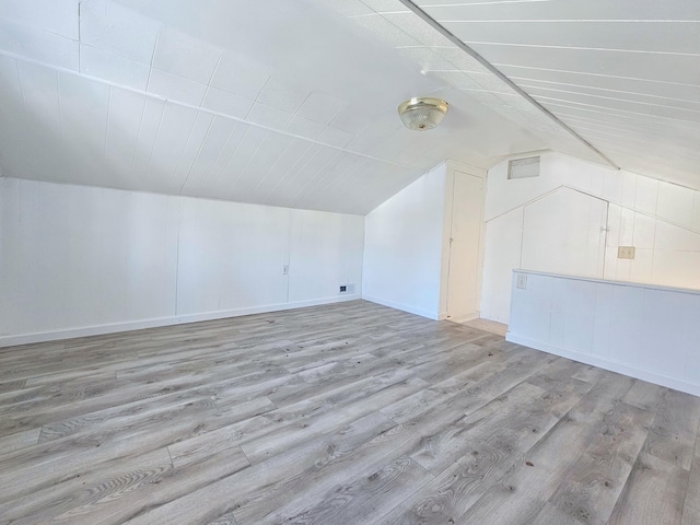 additional living space with light hardwood / wood-style flooring and lofted ceiling